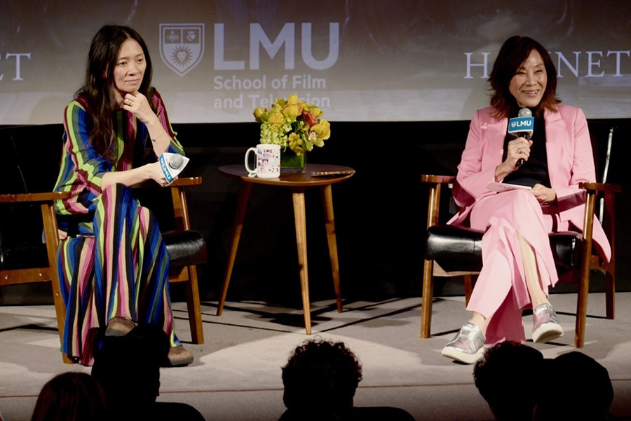 Director Chloé Zhao and Janet Yang holding microphones