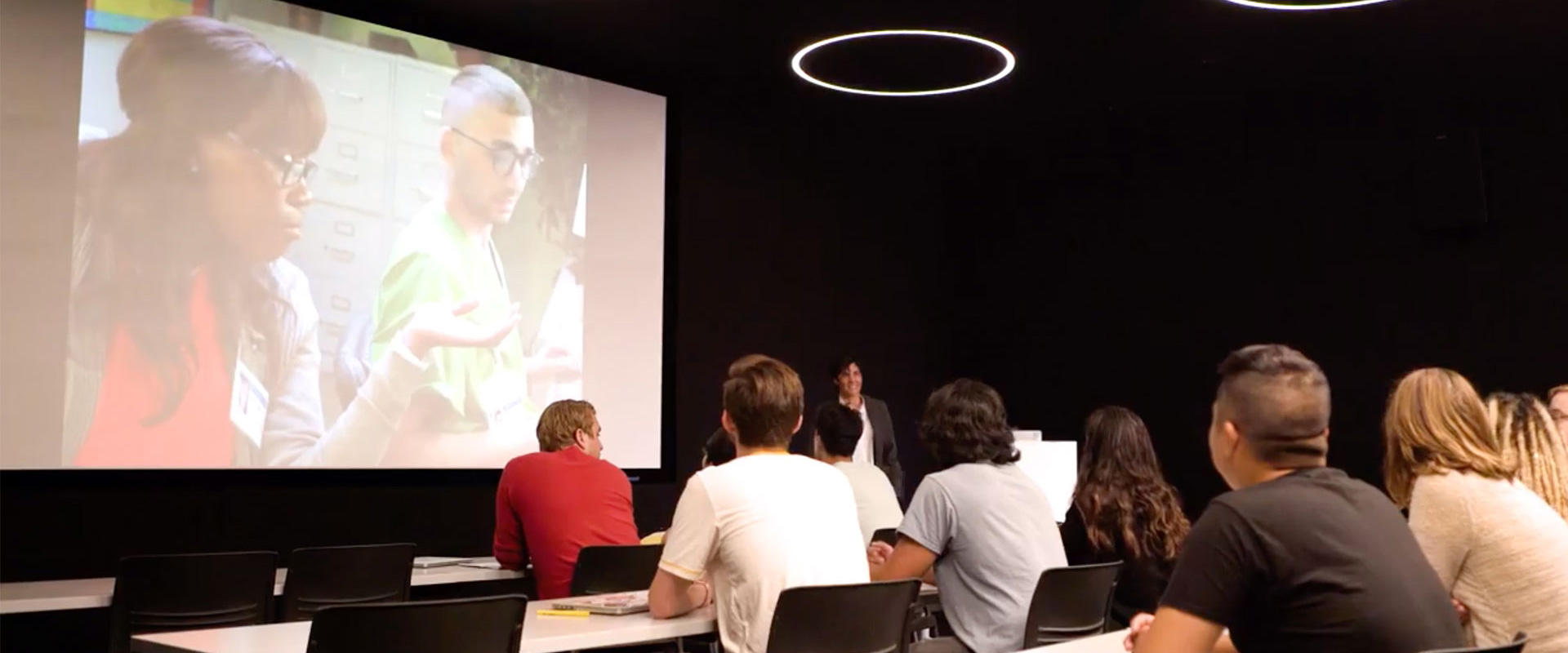 Students in a theater classroom watching a film