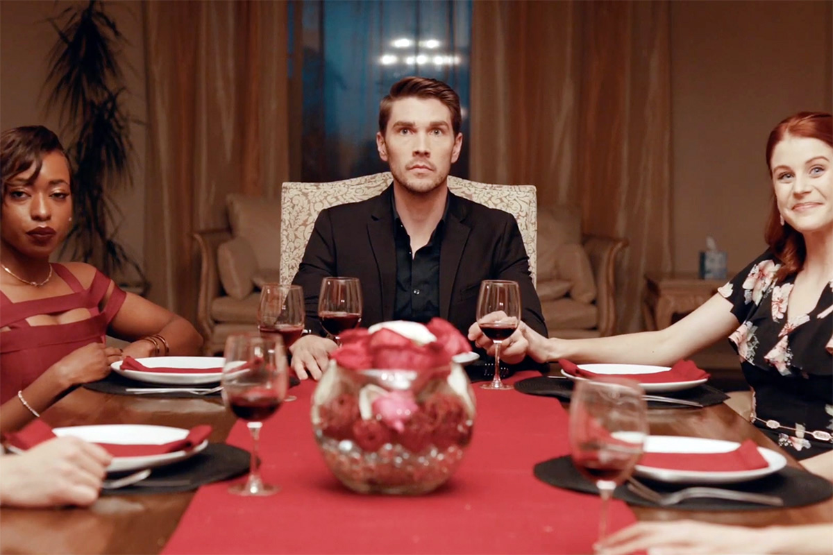 A scene depicting several nicely-dressed people seated around a dinner table